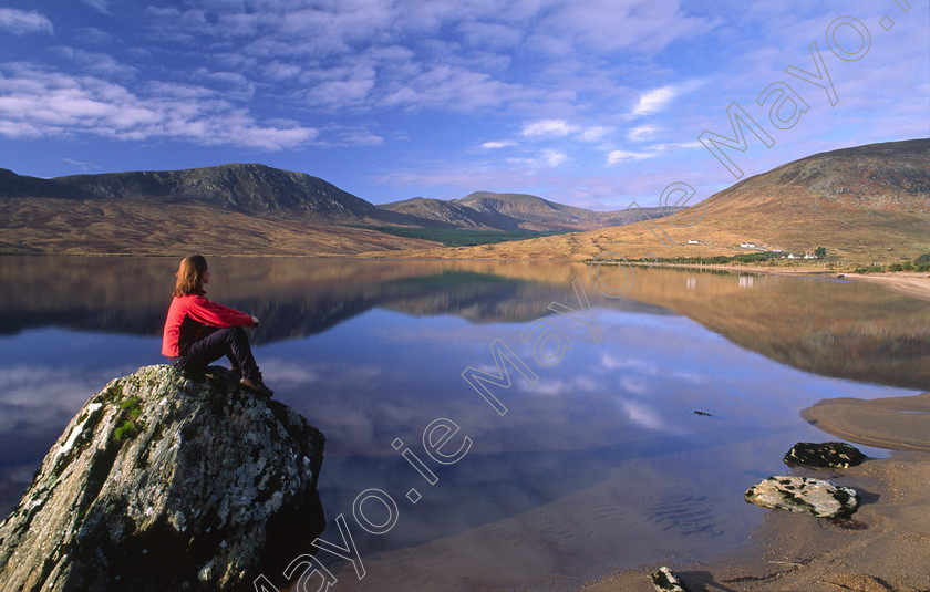 Taking-time-out-in-the-Nephin-Wilderness-Area 
 Person looking over Lough Feeagh, Nephin Beg Mountains, Co Mayo, Ireland. 
 Keywords: Irish, hills, mountains, peaks, landscapes, outdoors, scenery, scenes, loughs, lakes, reflections, reflected, beach, beaches, sand, sandy, shore, shorelines, boulders, rocks, calm, peaceful, meditation, person, figure, woman, contemplation, thought