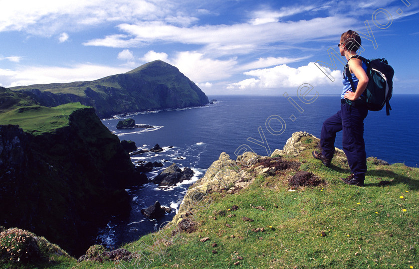 Walking-on-Clare-Island 
 Walker admiring the seacliffs of north Clare Island, Co Mayo, Ireland. 
 Keywords: Irish, walks, walking, walkers, treks, trekking, trekkers, hikes, hiking, hikers, coast, coastlines, coastal, atlantic, sea, ocean, cliffs, seacliffs, clifflines, islands, outdoors, scenery, scenes, views, mountains, hills