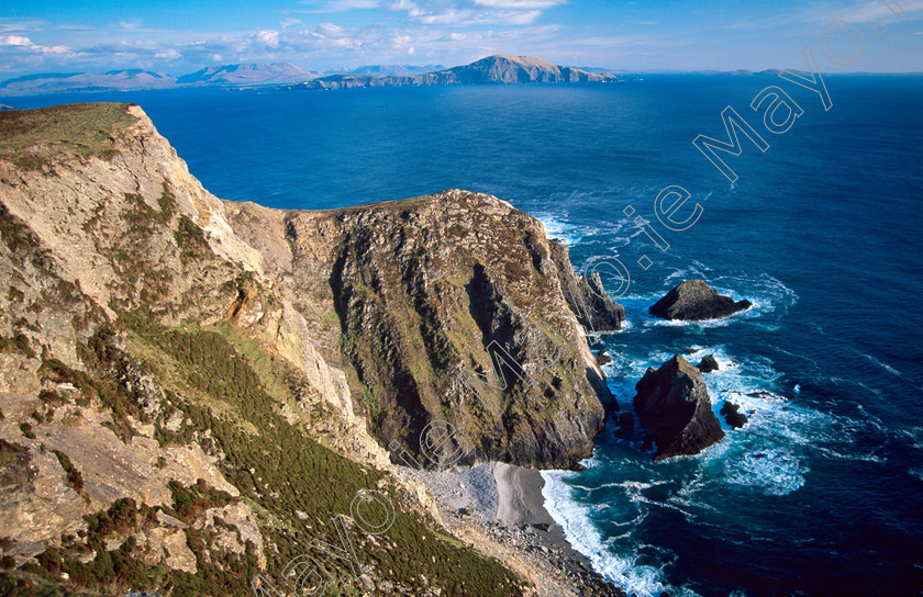 Cliffs-on-Inishturk 
 Dooega Head and Clare Island, from Achill Island, Co Mayo, Ireland. 
 Keywords: Irish, islands, cliffs, clifflines, seacliffs, mountains, hills, outdoors, landscapes, scenery, shores, shorelines, coasts, coastlines, coastal, atlantic, seas, oceans, Menaun, heights, Menawn